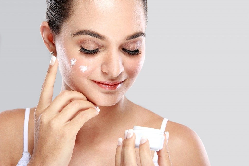 woman applying moisurizer on her face