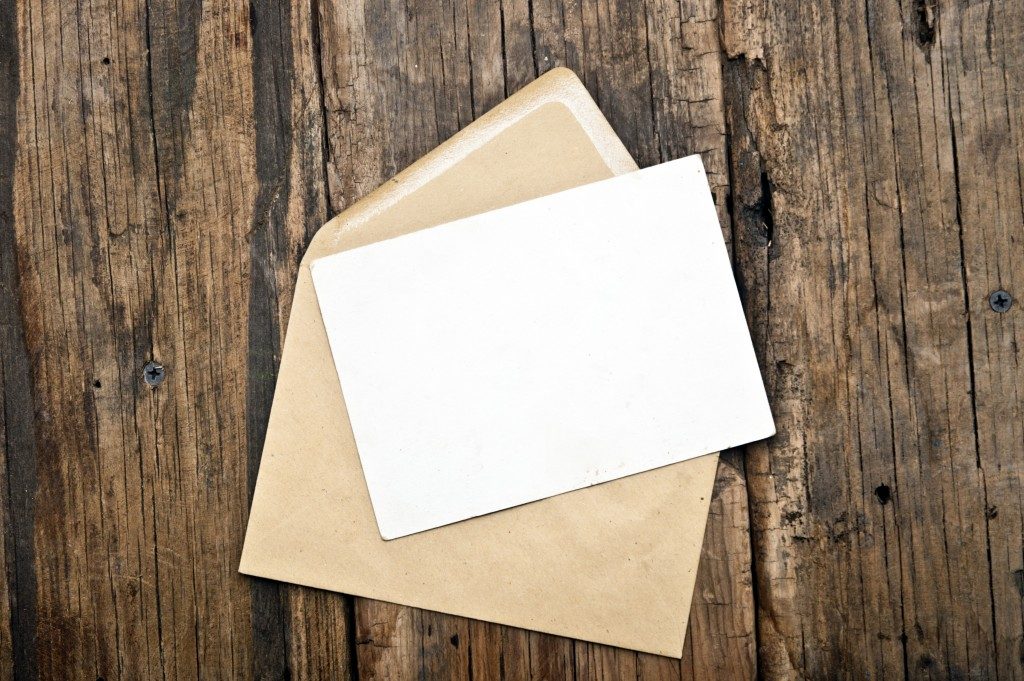 Blank card and envelope on old wooden background