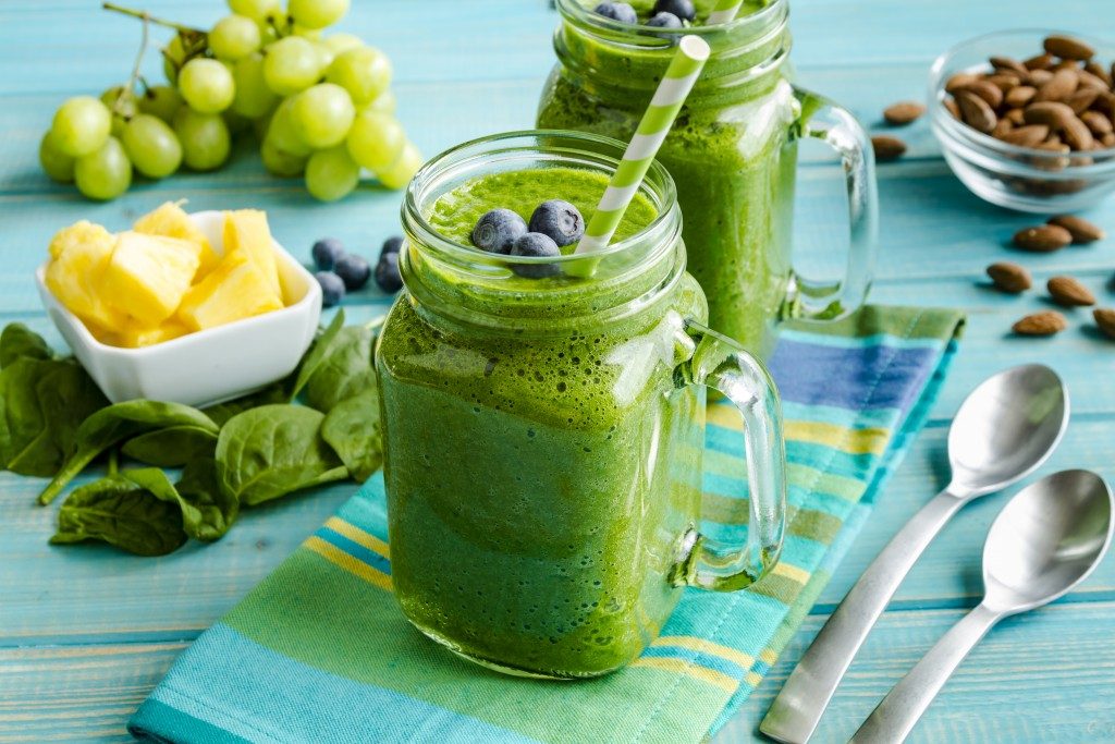 Mason jar mugs filled with green spinach and kale health smoothie