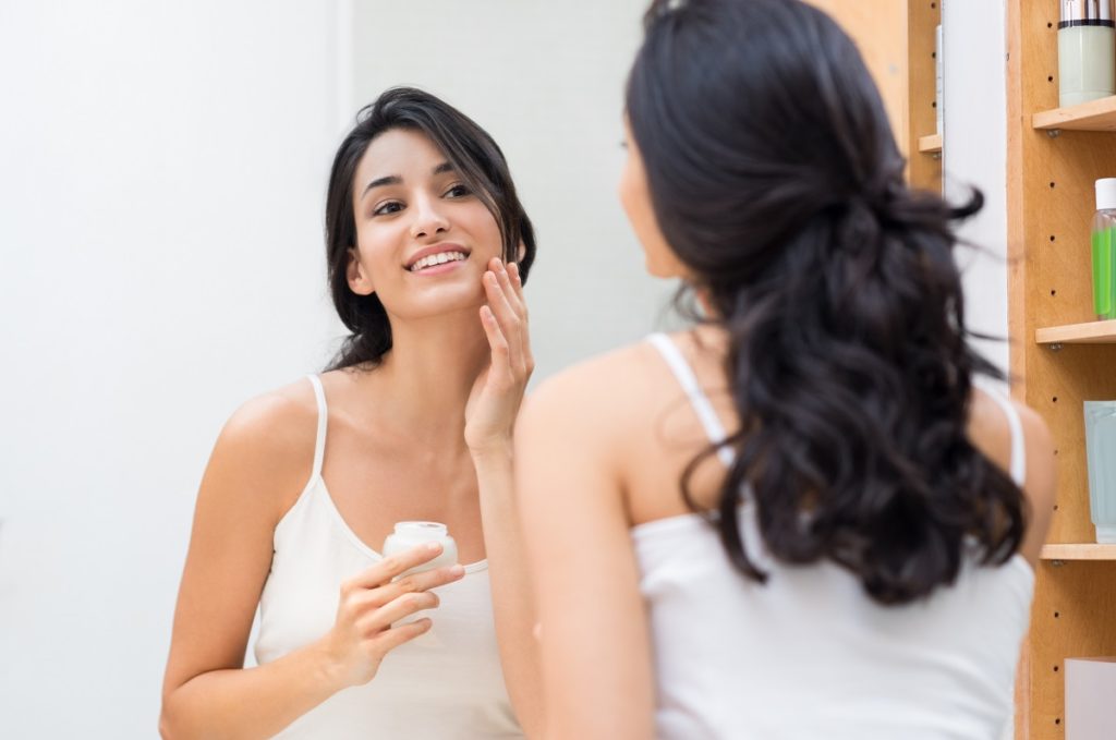 woman putting cream on her face